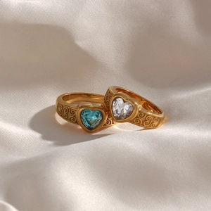 Close-up of golden heart rings with blue and clear zircon and vintage engravings