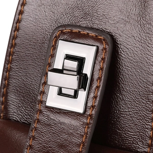 Macro shot of brown leather texture with yellow stitching and silver twist lock detail