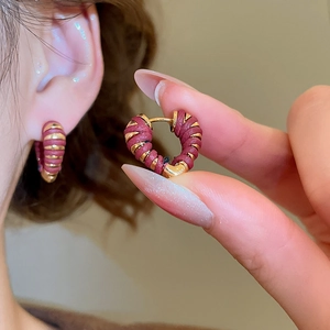 Vue macro des boucles d'oreilles cœur 18k avec détails en cuir tressé bordeaux