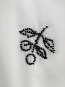 Detailed view of handmade black beaded floral pattern on soft white fabric blouse