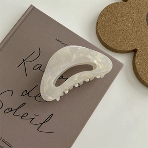 Dettaglio molletta per capelli bianco madreperla su uno sfondo di libro francese vintage