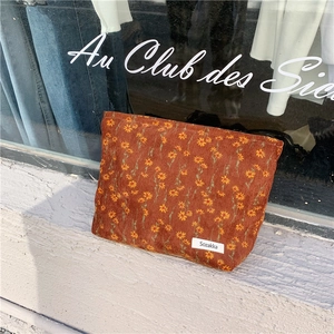 Détail d'une trousse de maquillage en velours côtelé avec motifs floraux vintage orange