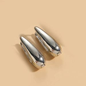 Close-up of polished silver teardrop hoop earrings with high-shine metallic finish