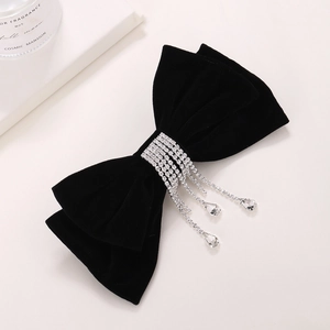 Elegant black velvet bow hair clip with silver rhinestone tassels on beige background