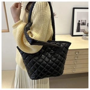 Grand sac cabas noir matelassé avec surpiqûres en losanges porté à l'épaule élégamment