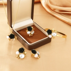 Close-up of gold jewelry set with black rose, pearl accents, and crystal details