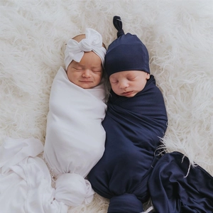 Soft newborn swaddle blanket set with white bow headband and blue knotted hat detail