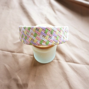Detailed close-up of a colorful woven raffia headband showing texture and fabric edge