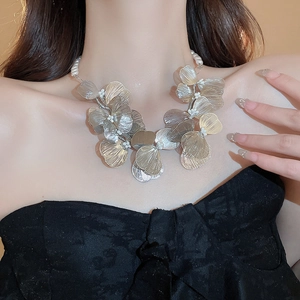 Detail of hollow metal flower necklace with pearl bead center and brushed texture finish