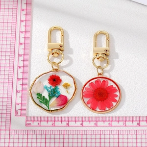 Handmade pressed flower resin keychain with colorful dried petals on a white background
