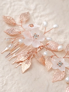 Detailed macro of rose gold bridal hair comb with pearls, white flowers and rhinestones