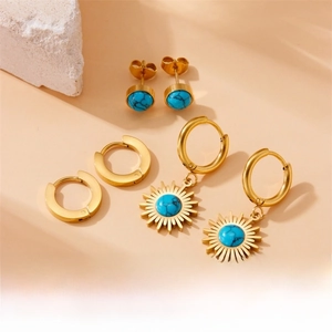 Detail view of vintage gold earring set with turquoise stone charms on a stone display