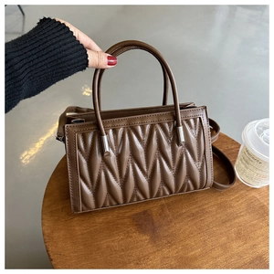 Close-up of brown quilted PU leather handbag with silver hardware and top handle
