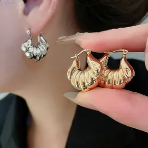 Chic gold and silver croissant hoop earrings with a polished metallic shell texture