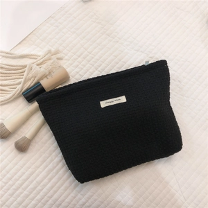 Detail of black waffle texture makeup bag with simple wish label and cosmetics