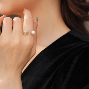 Detail of a C-shaped open ring with a white pearl and a pave-set diamond sphere