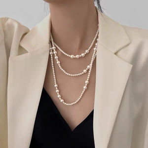 Close-up of triple-layered irregular pearl necklace styled with a beige blazer