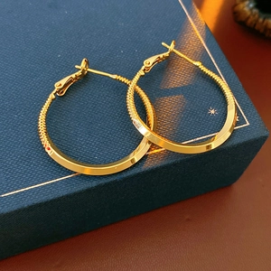 Close-up of gold twisted hoop earrings placed on a deep blue luxury jewelry gift box