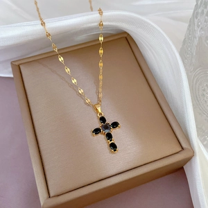 Luxurious gold cross necklace with black stones on white silk in a jewelry gift box