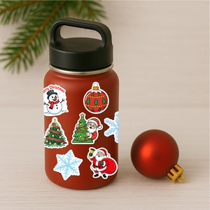 Close-up of festive Christmas vinyl stickers on a red tumbler with snowman and tree patterns