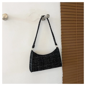 Détail de la texture en tweed noir et blanc d'un sac baguette avec boucle métallique