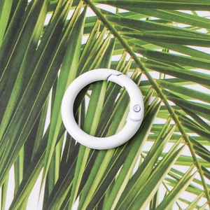 Detailed view of a white 23mm round metal spring ring buckle on a palm leaf background