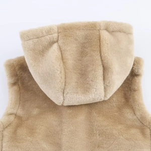 Gros plan d'un gilet à capuche en fausse fourrure beige montrant sa texture pelucheuse