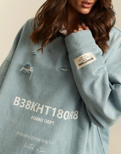 Detailed view of the distressed light blue hoodie with FOMO DEPT. printed lettering