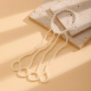 Detail of layered pearl slave bracelet featuring wrist and finger rings on stone plate