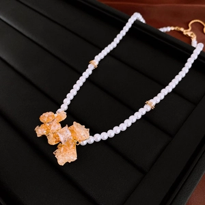 Macro detail of amber crystal flower and pearl necklace on black leather display