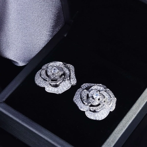 Detailed close-up of silver rose-shaped stud earrings with micro-inlaid zircons in a box