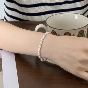 Detail of 925 sterling silver woven rope bracelet on wrist in a coffee shop setting