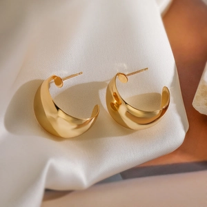 Gros plan de boucles d'oreilles en C plaquées or 18 carats sur du tissu de soie blanc