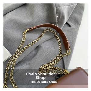 Détail de la bandoulière en chaîne dorée avec renfort en cuir marron du petit sac carré
