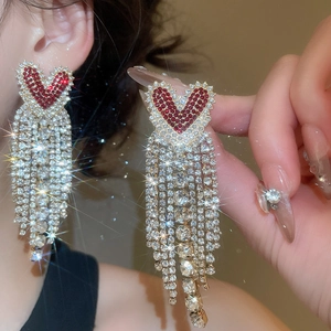 Macro shot of elegant red heart rhinestone earrings with long shimmering tassels