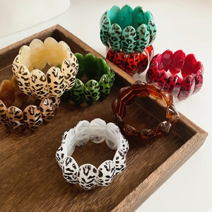 Detailed view of colorful leopard print acrylic resin bracelets on a wooden tray
