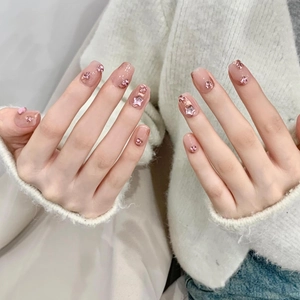 Macro shot of handmade press-on nails with pink glitter, rhinestones and star charms