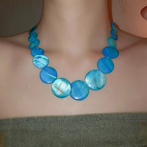 Detailed view of large blue mother of pearl shell disc beads on a beach style necklace
