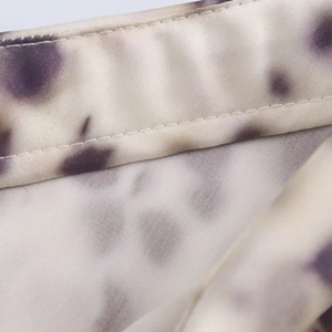 Macro detail of purple marble print satin fabric with fine stitching and glossy finish