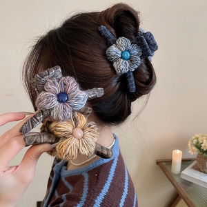Detail of knitted flower hair claw clips with plaid fabric wrap and central pearl bead