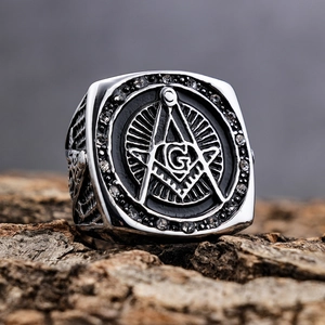 Makroaufnahme des silbernen Freimaurer-Rings mit G-Symbol auf Holzgrund