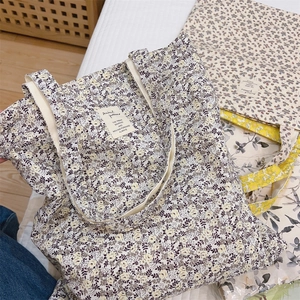 Floral canvas tote bag with purple flower pattern and double handles in a cozy home setting