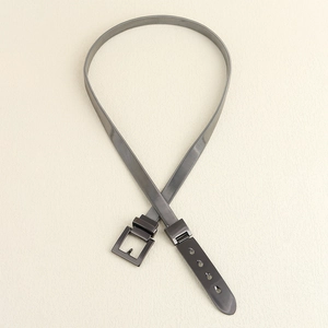 Detail of grey metal mesh waist belt featuring a square buckle and adjustable eyelets