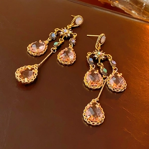 Detail of vintage gold tassel earrings with pink crystal teardrops on brown leather