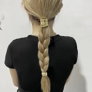 Detail of a gold wavy textured metal ponytail cuff shown on a model's hair
