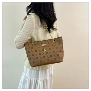 Detail of vintage pattern tote with golden chain strap and a deer pendant on a model