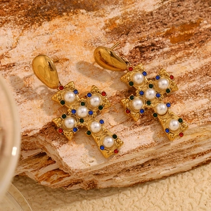 Detailed macro of vintage gold cross earrings with pearls and colorful rhinestones