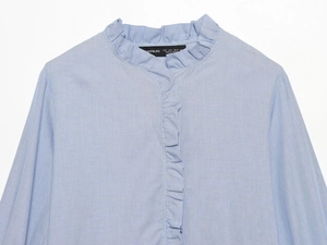 Detailed flat lay of blue striped poplin shirt with ruffle collar and decorative layers