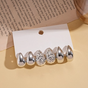 Set of 6 silver teardrop earrings with smooth and hammered finishes on a display card