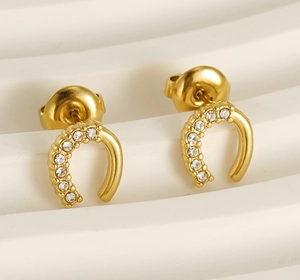 Détail de boucles d'oreilles fer à cheval dorées ornées de zircons cubiques brillants